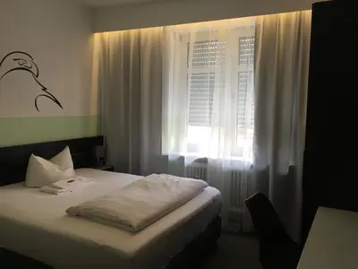 Ein Bett oder Betten in einem Zimmer der Unterkunft Hotel Augsburg Goldener Falke